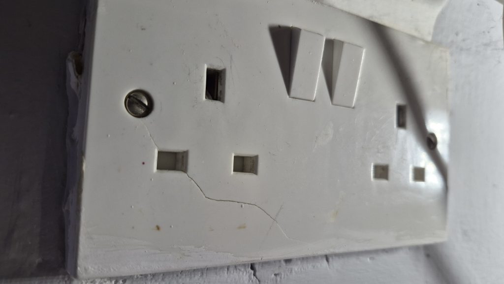 Cracked and worn electrical socket showing signs of age and damage