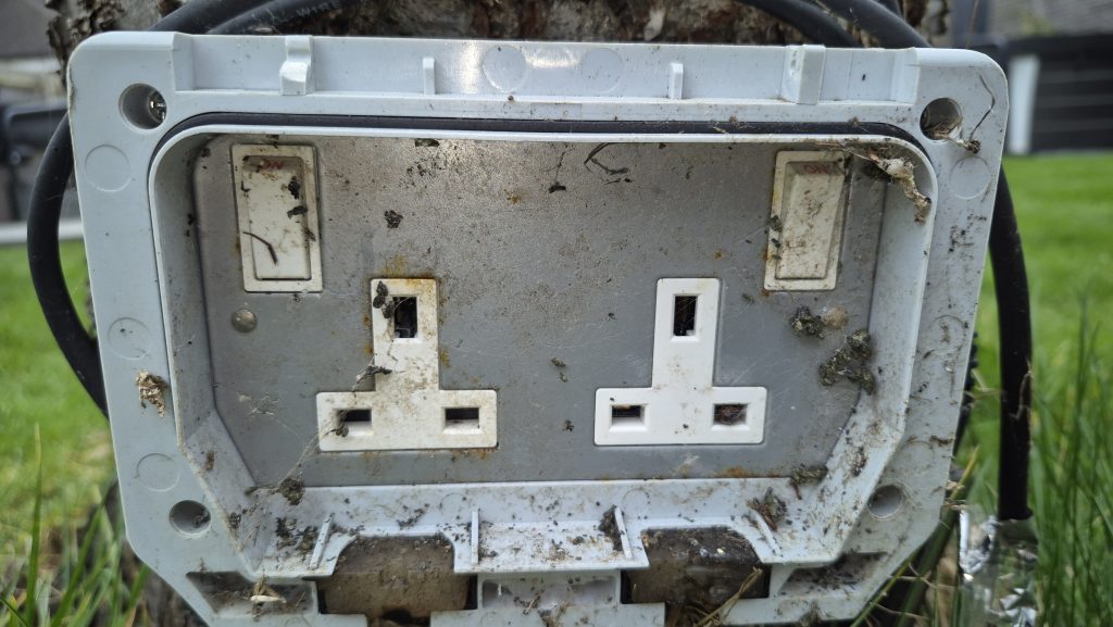Outdoor socket damaged by moisture and dirt causing intermittent electrical faults