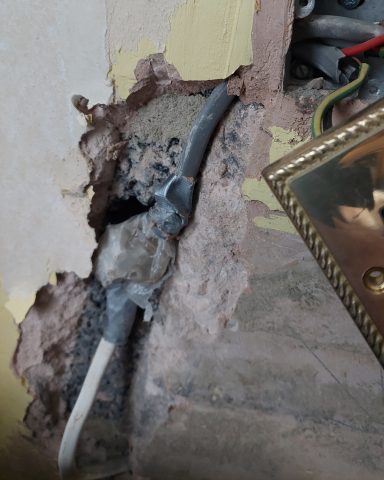 Unsafe electrical cable hidden in plaster identified during repair work.